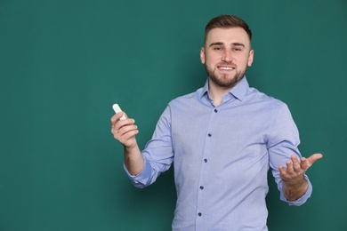 Photo of Portrait of young teacher with chalk on green background. Space for text