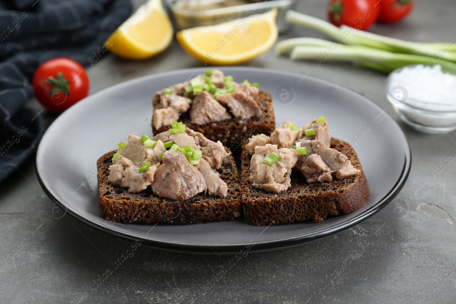 Photo of Tasty sandwiches with cod liver and green onion on light grey table