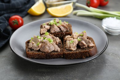 Photo of Tasty sandwiches with cod liver and green onion on light grey table