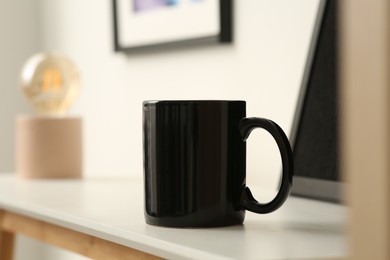 Photo of Black mug on white table indoors. Mockup for design