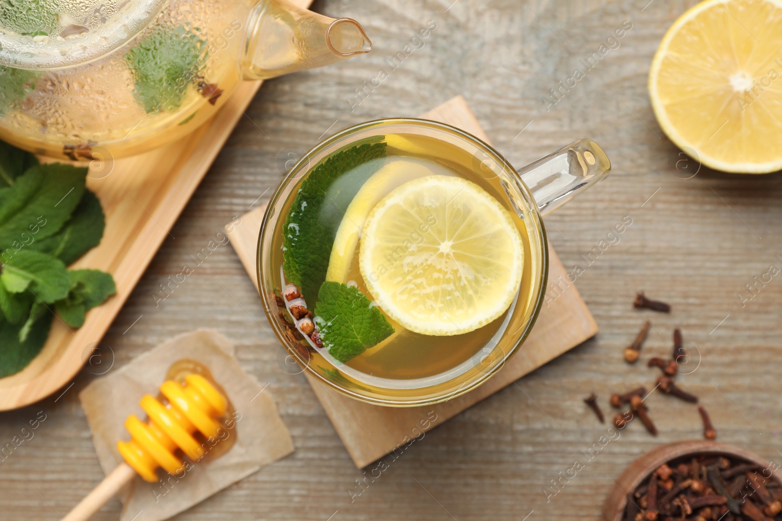 Photo of Glass cup of immunity boosting drink and ingredients on wooden table, flat lay