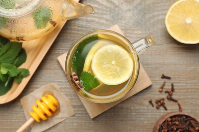 Glass cup of immunity boosting drink and ingredients on wooden table, flat lay