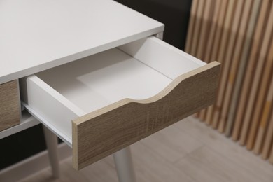 Photo of Stylish desk with open empty drawer in office