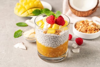 Delicious chia pudding with mango, raspberries and granola on light grey table