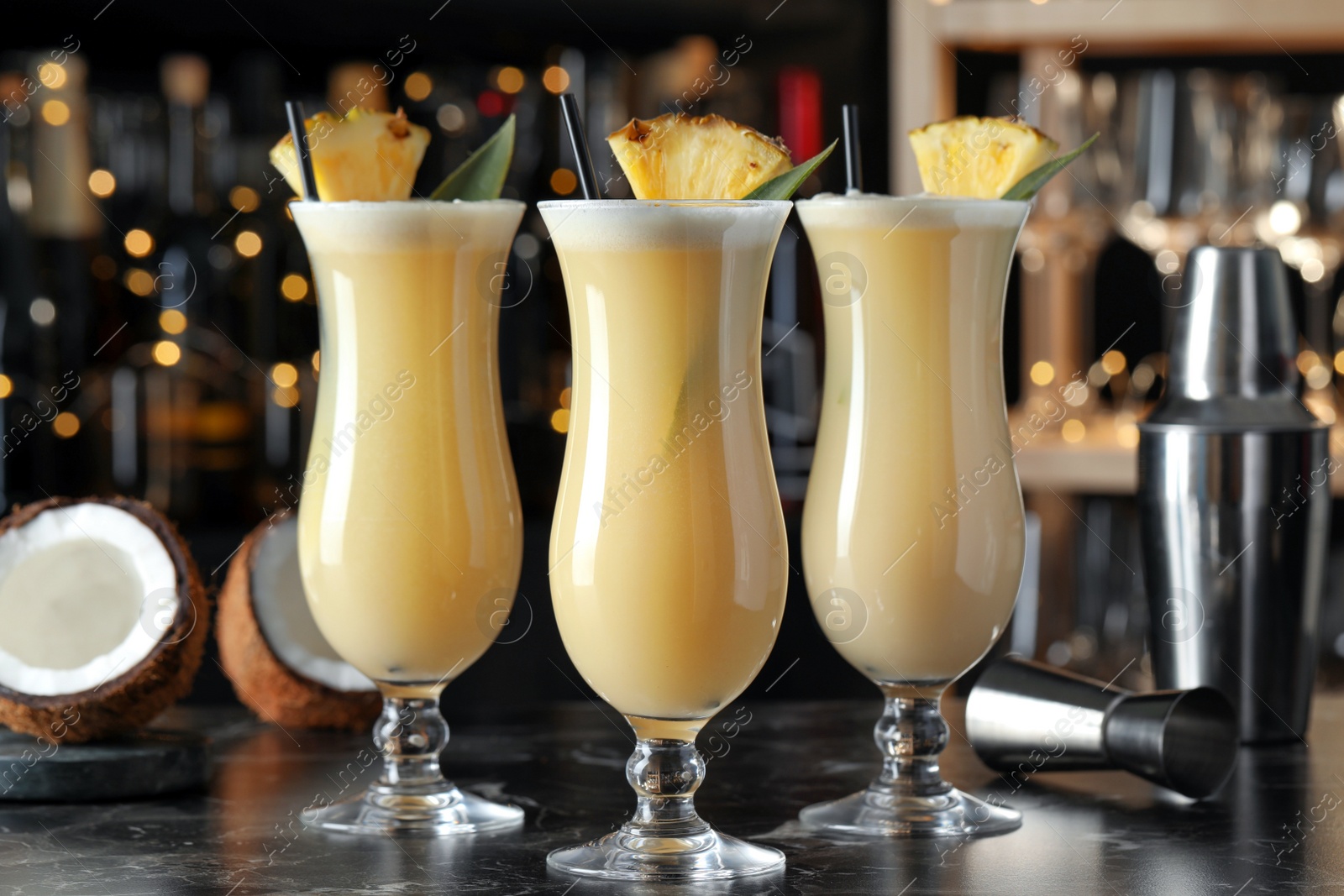 Photo of Tasty Pina Colada cocktails on black marble bar countertop