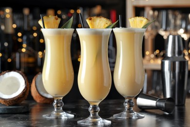 Photo of Tasty Pina Colada cocktails on black marble bar countertop