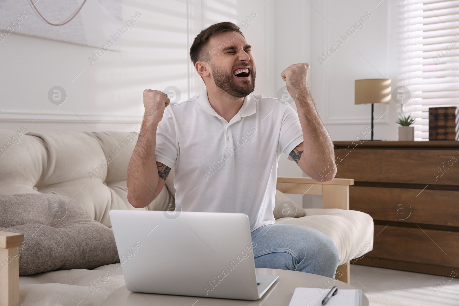 Photo of Emotional man participating in online auction using laptop at home