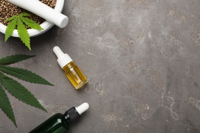 Photo of Hemp oil, seeds and leaves on grey background, flat lay. Space for text