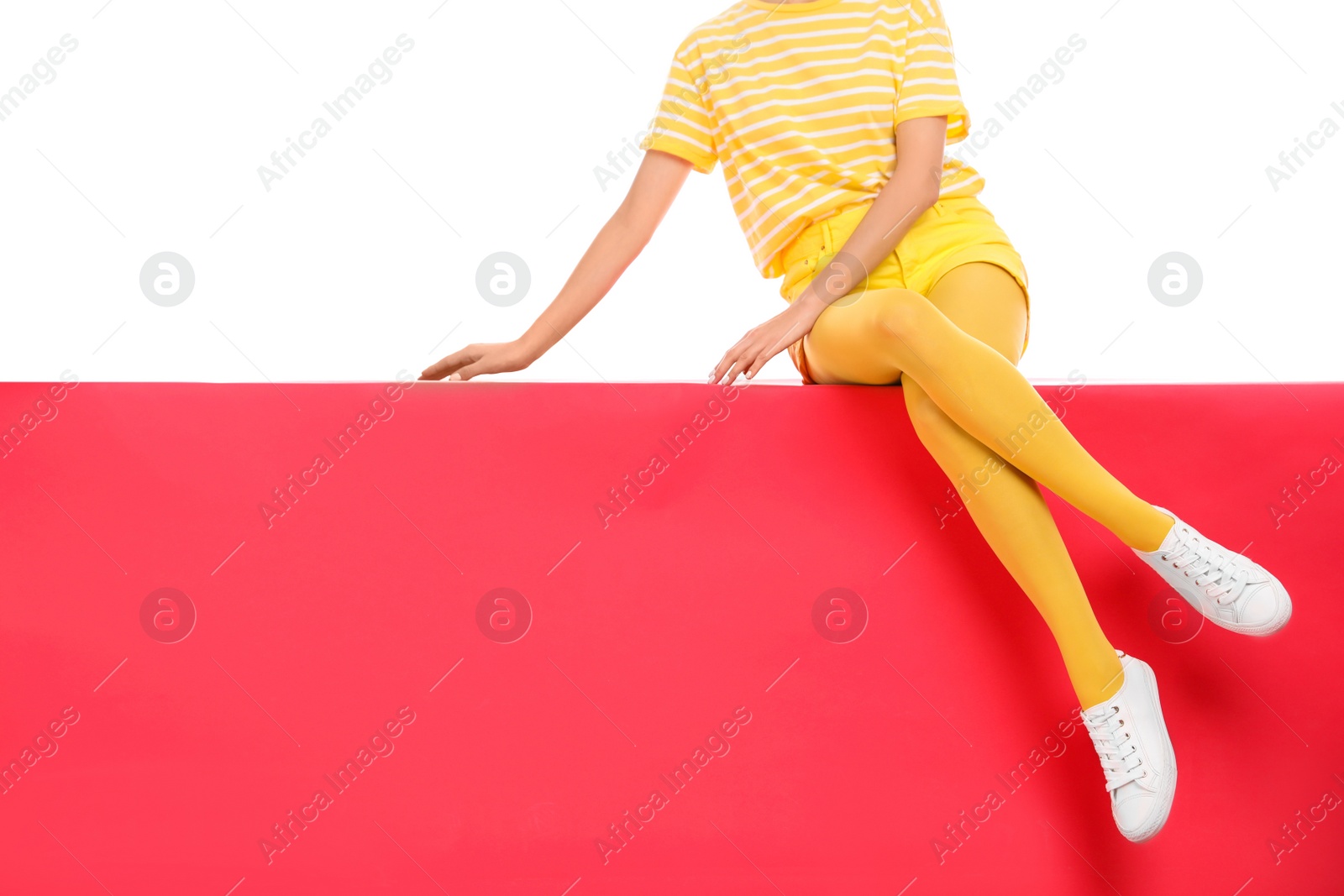 Photo of Woman wearing yellow tights sitting on color background, closeup. Space for text