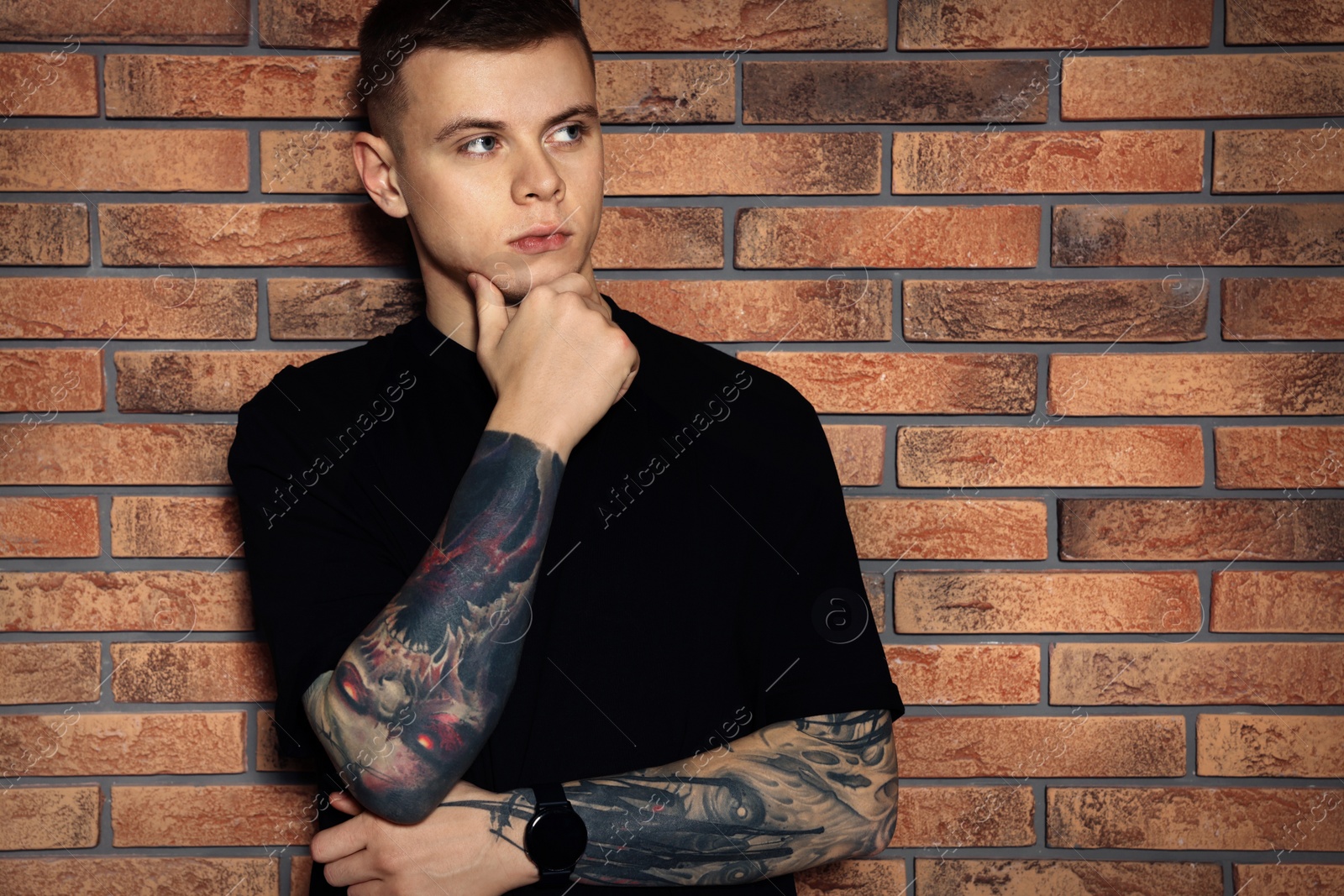 Photo of Young man with tattoos near brick wall