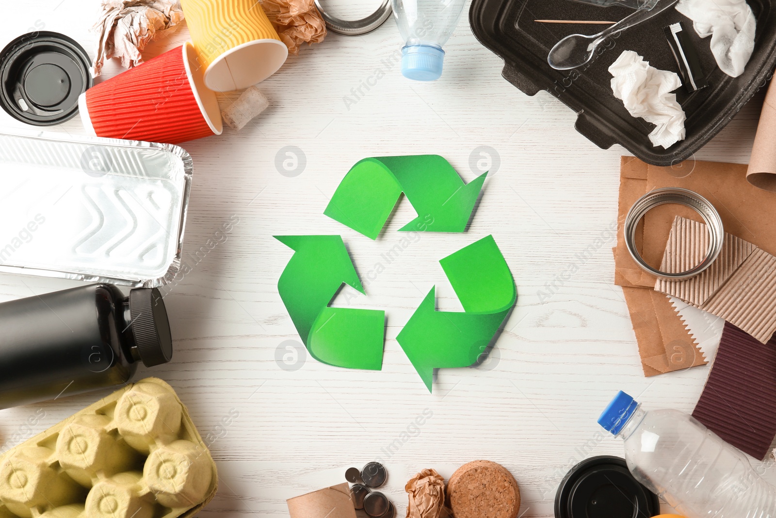 Photo of Recycling symbol and different garbage on wooden background, top view