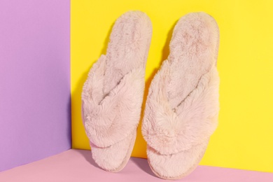 Pair of soft slippers on color background