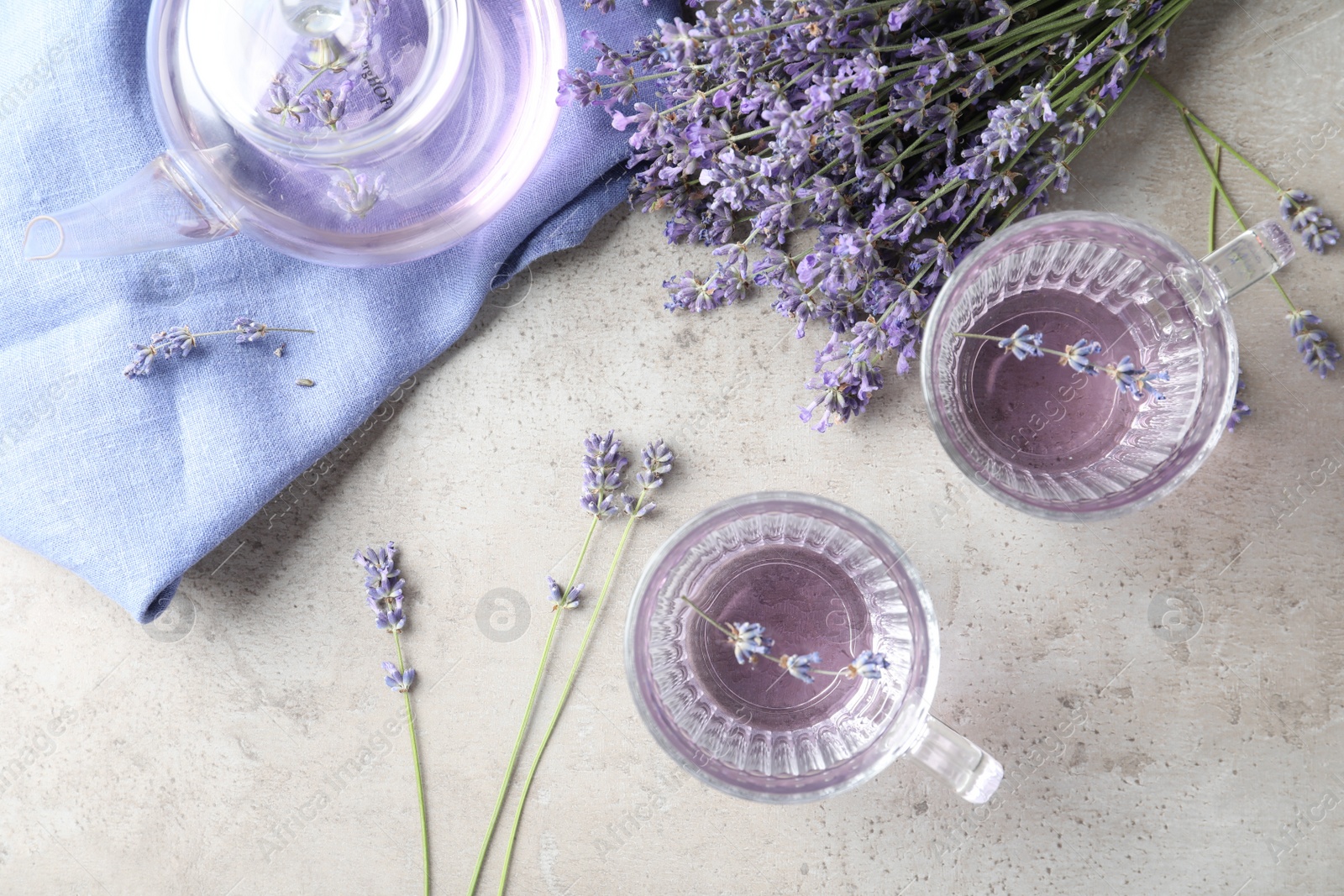 Photo of Fresh delicious drink with lavender in glass cups on grey table, flat lay