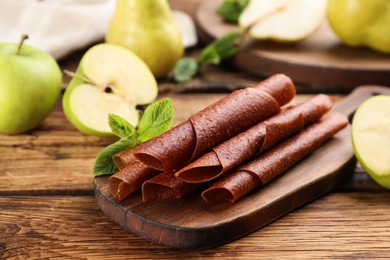 Photo of Composition with delicious fruit leather rolls on wooden table, closeup