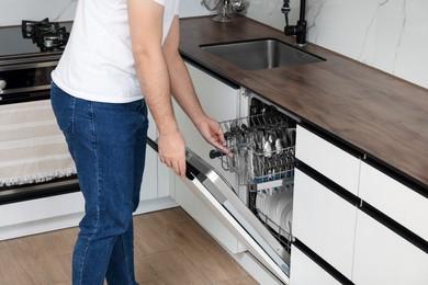Photo of Man closing dishwasher's door in kitchen, closeup