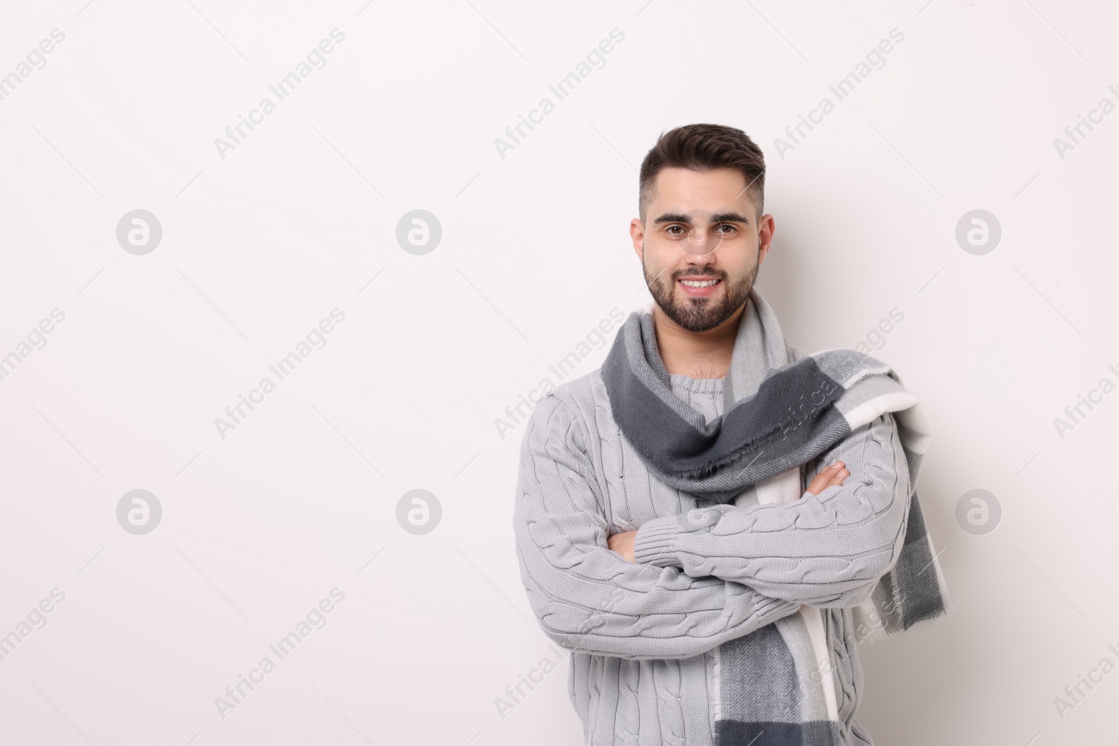 Photo of Portrait of smiling man in warm scarf on light background. Space for text