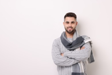 Portrait of smiling man in warm scarf on light background. Space for text