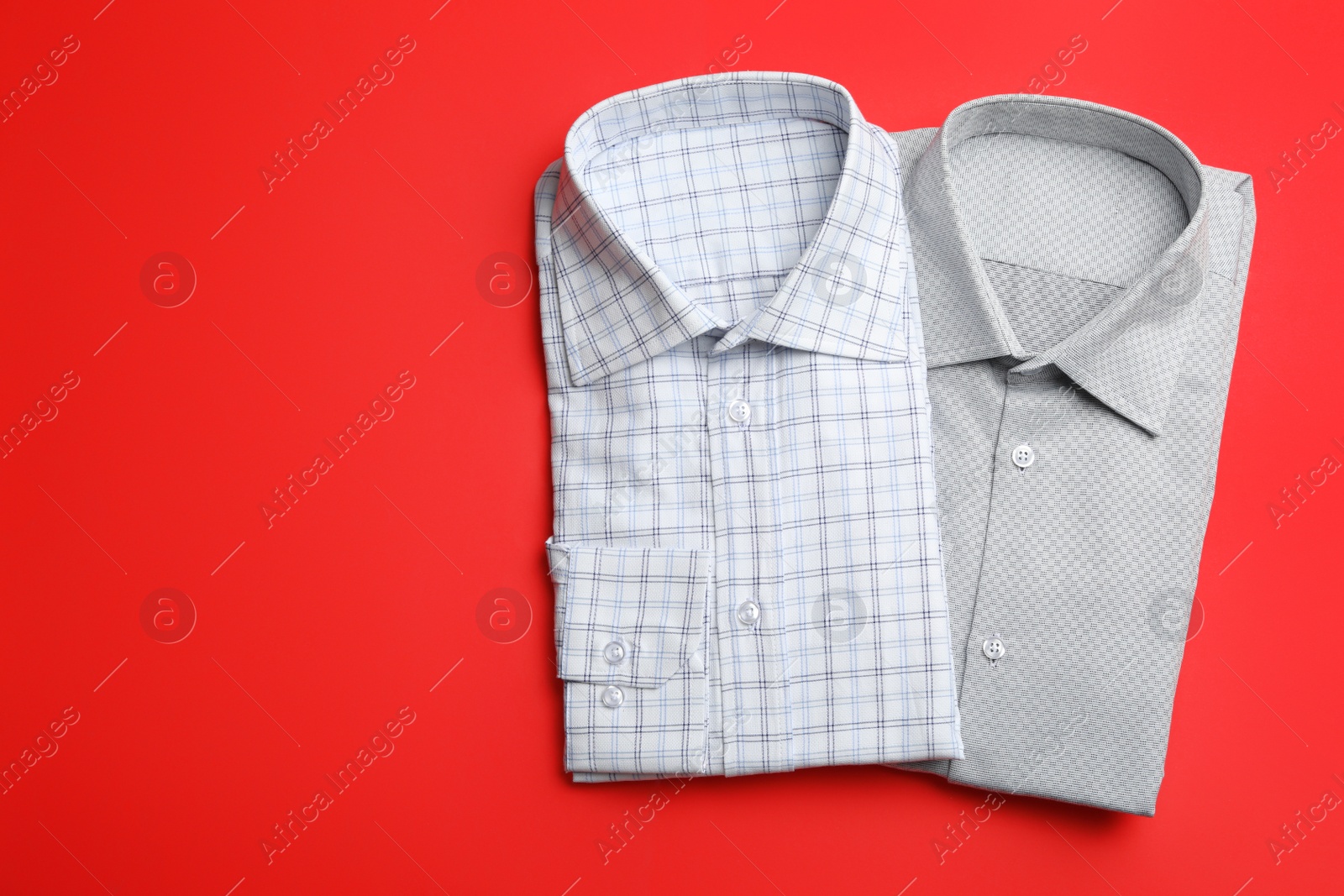 Photo of Stylish male shirts on red background, flat lay. Space for text