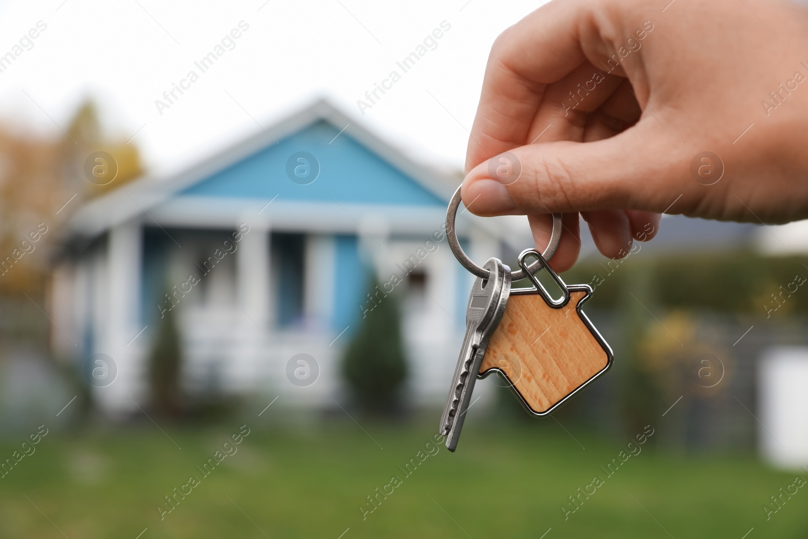 Photo of Woman holding house keys outdoors, closeup with space for text. Real estate agent