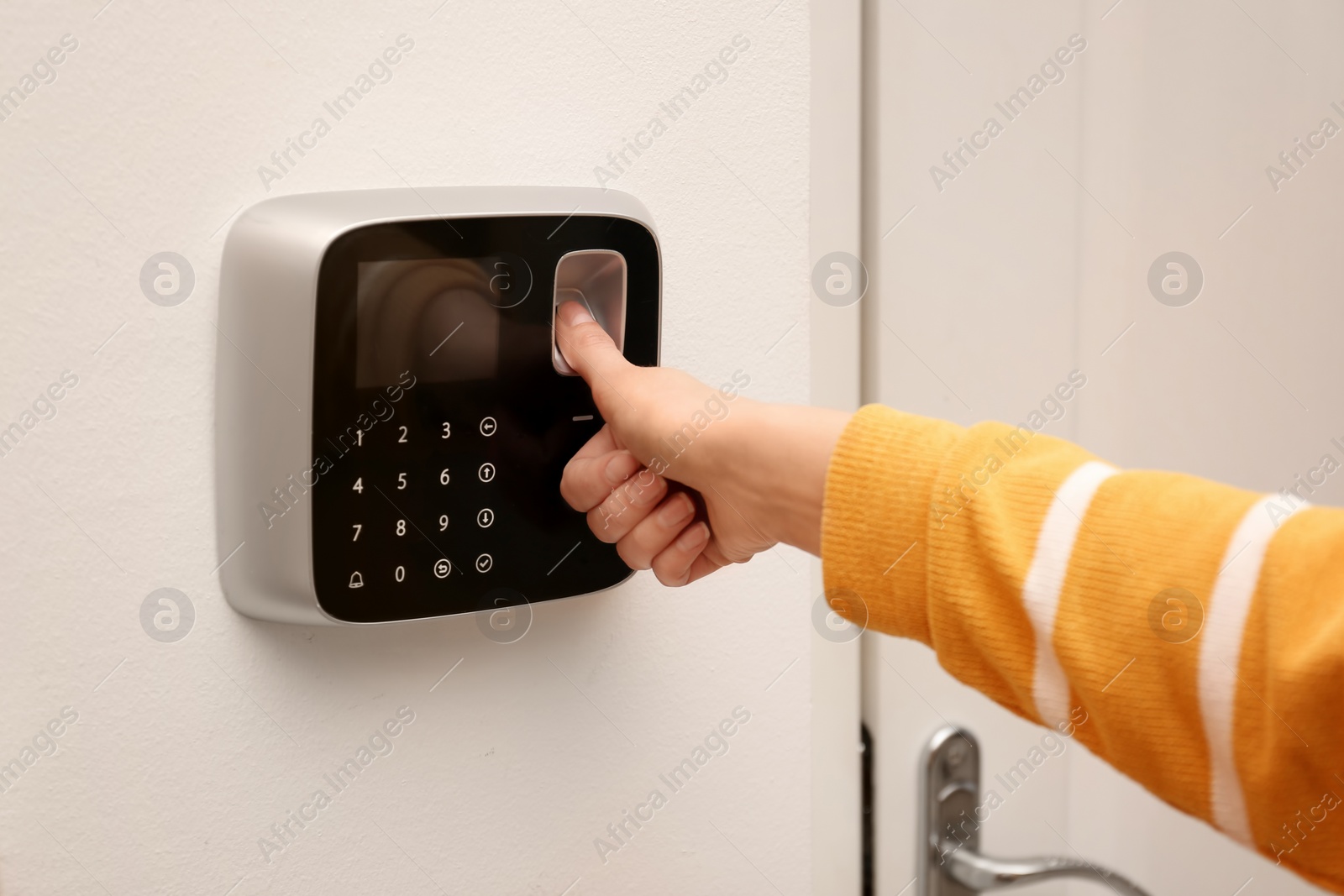 Photo of Woman scanning fingerprint on alarm system indoors, closeup