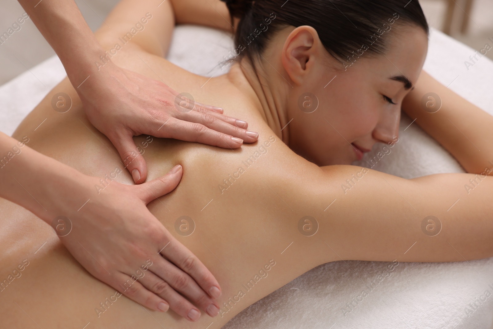 Photo of Woman receiving back massage on couch in spa salon