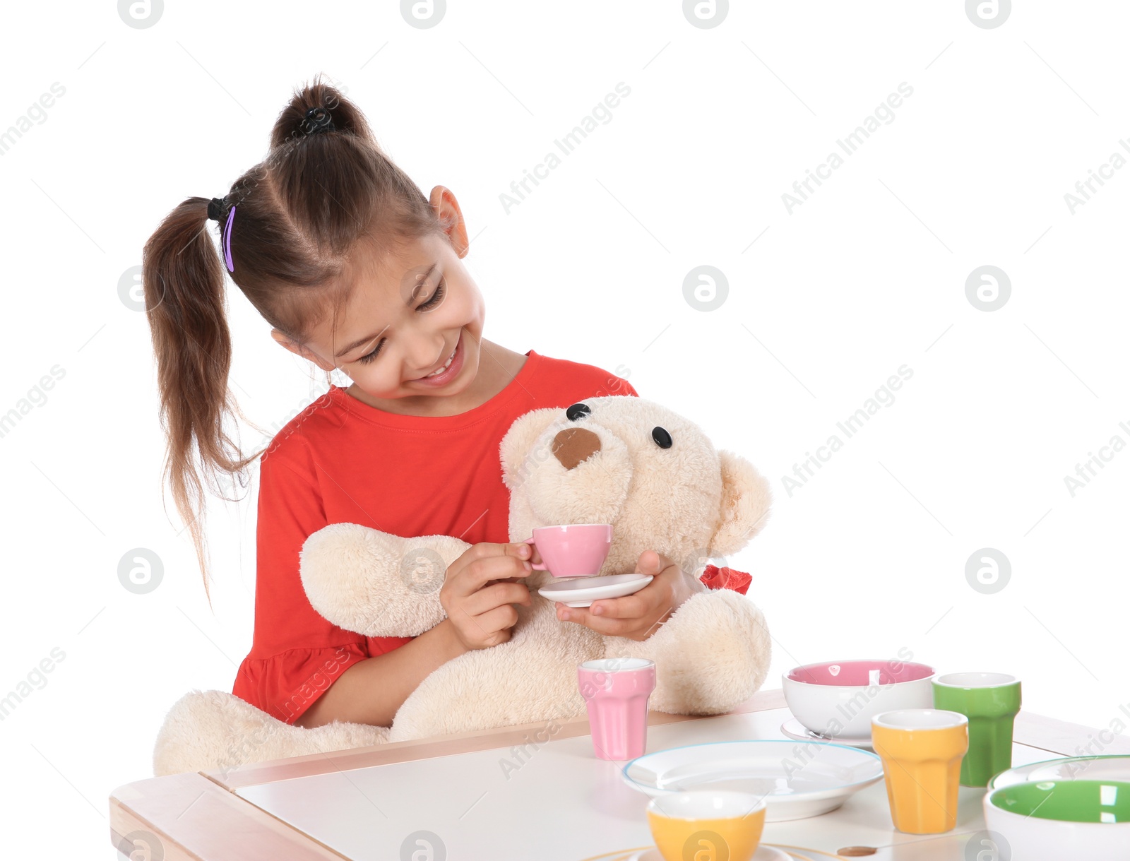 Photo of Little child playing tea party with toy on white background. Indoor entertainment