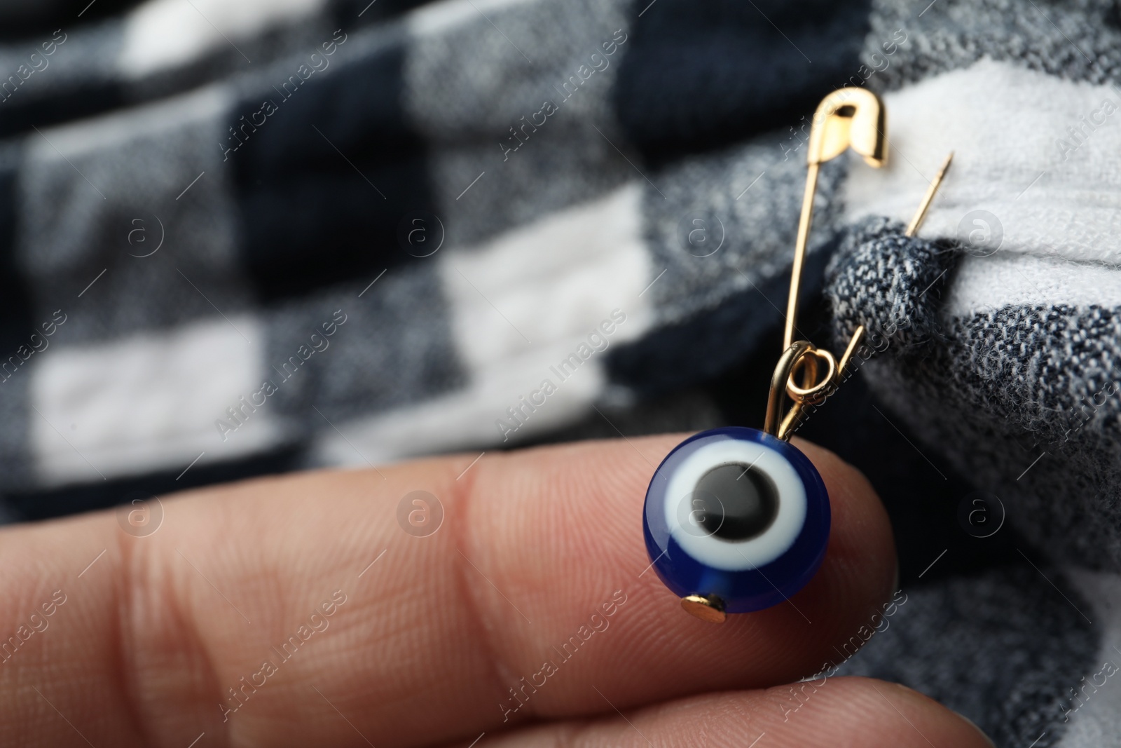 Photo of Woman pinning evil eye amulet on clothing, closeup