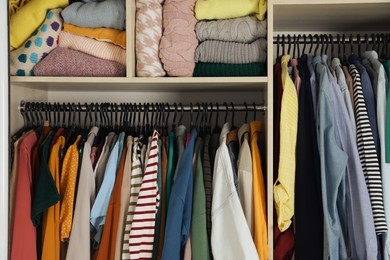 Photo of Wardrobe closet with different stylish clothes and home stuff. Fast fashion