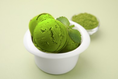 Tasty matcha ice cream with mint in bowl on pale green background, closeup