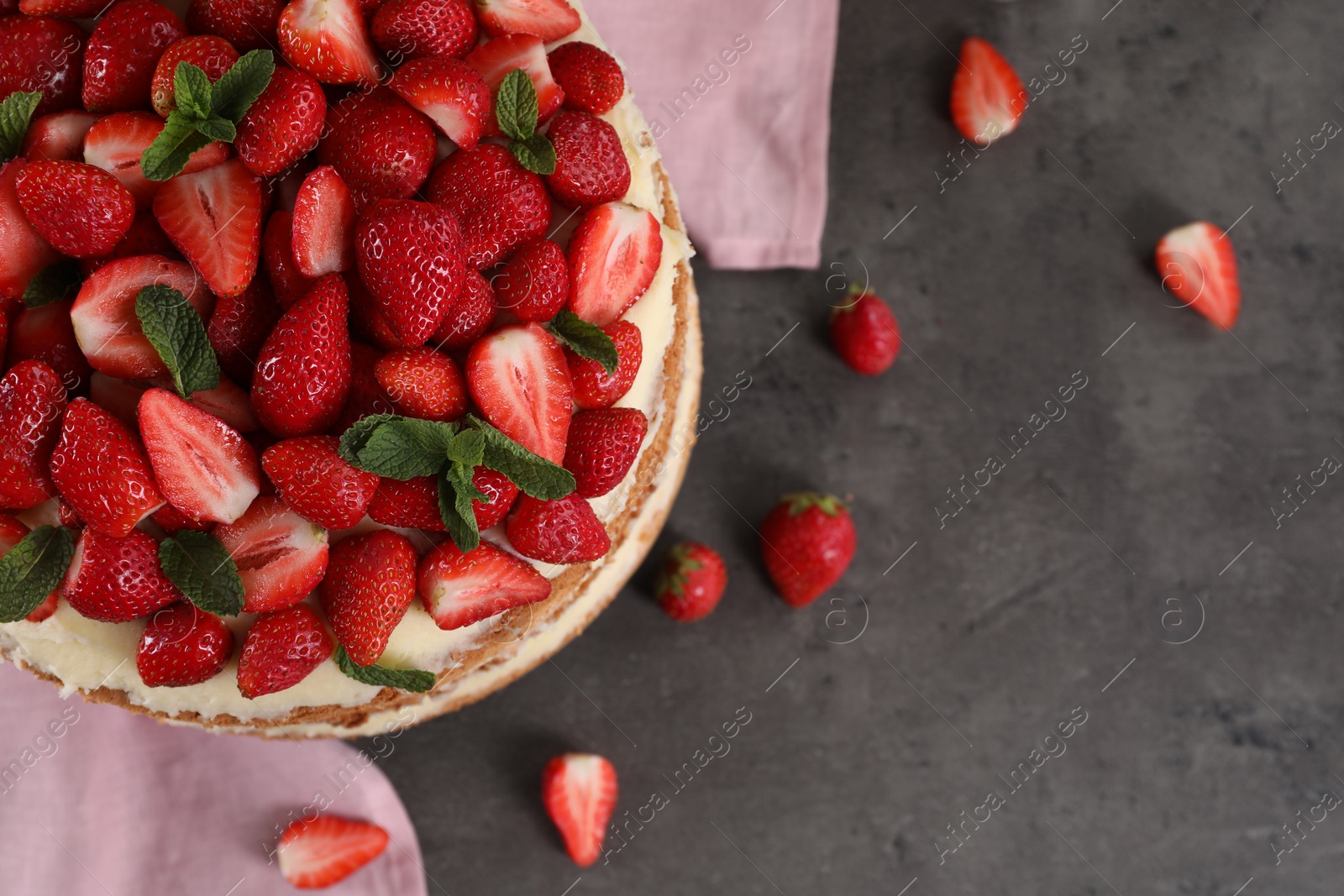 Photo of Tasty cake with fresh strawberries and mint on gray table, flat lay. Space for text