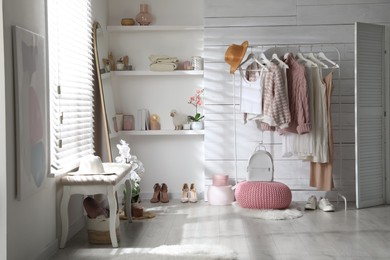 Photo of Rack with different stylish clothes, shoes and decorative elements in dressing room. Interior design