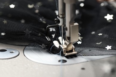 Sewing machine and black fabric with paillettes, closeup