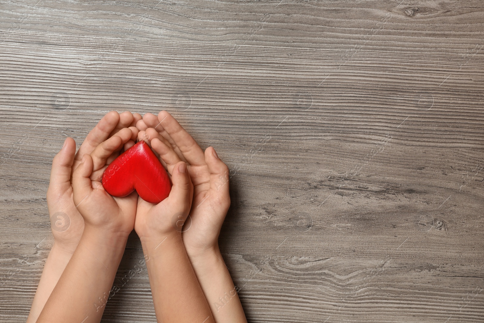 Photo of Woman and child holding heart on wooden background, top view with space for text. Donation concept