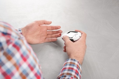 Man checking blood sugar level with glucometer at table. Diabetes test