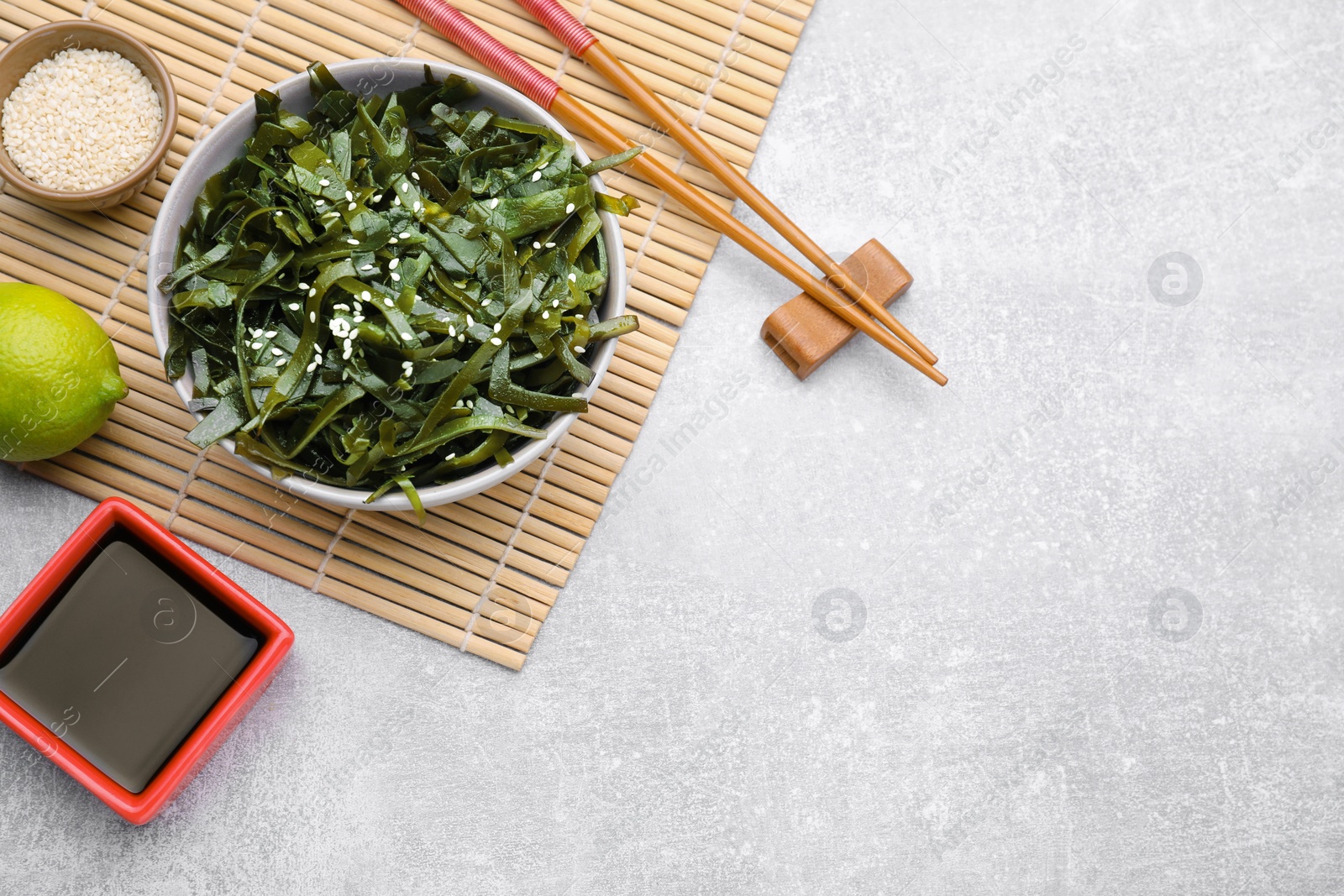 Photo of Fresh laminaria (kelp) seaweed served on light gray table, flat lay. Space for text