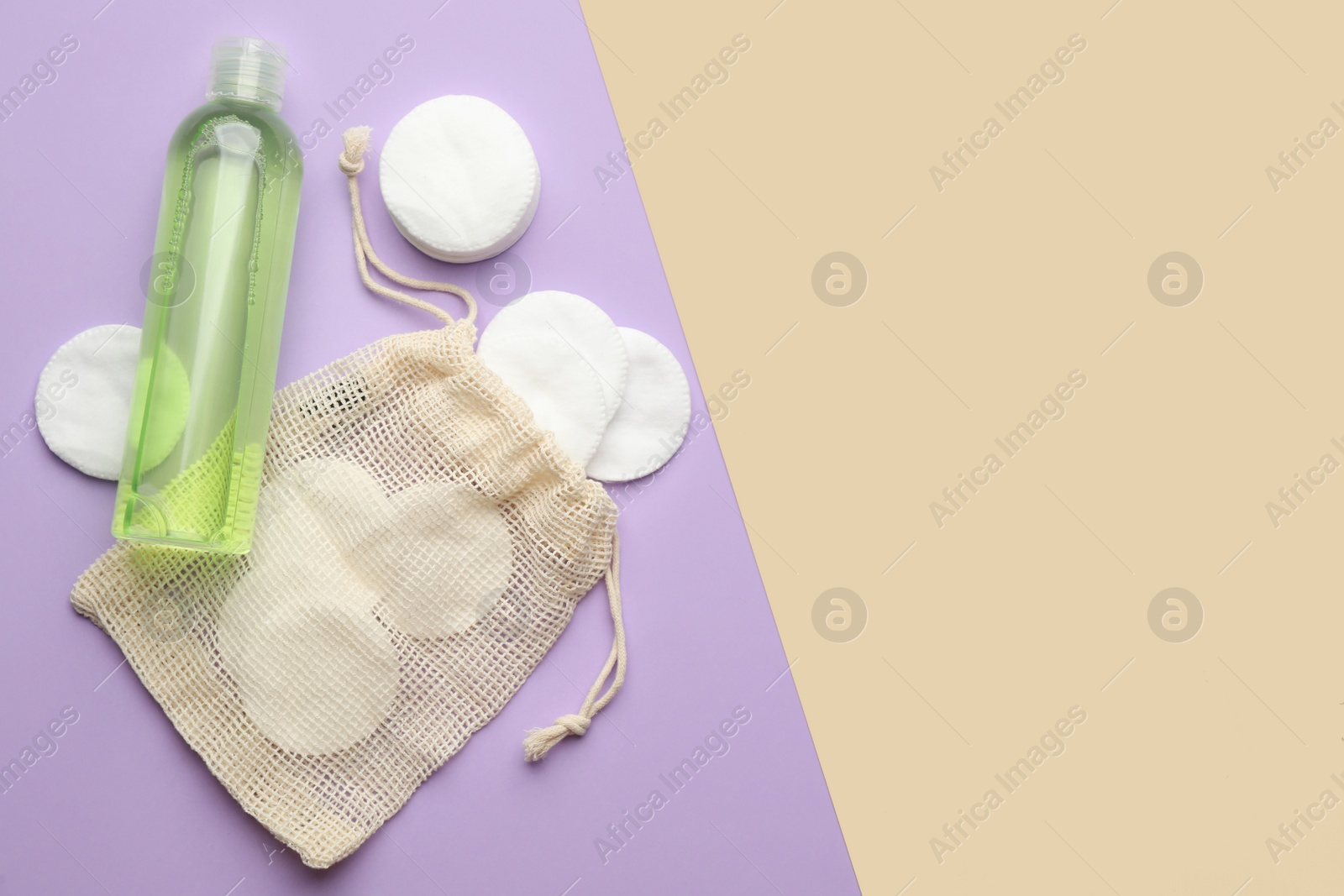 Photo of Cotton pads and makeup removal product on color background, flat lay. Space for text