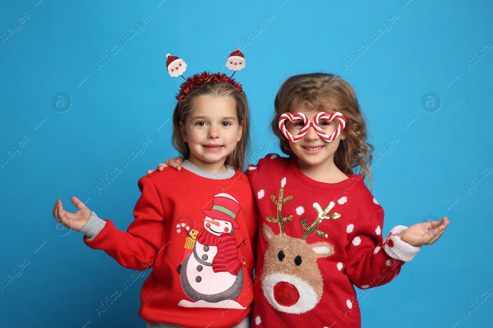 Photo of Kids in Christmas sweaters and festive accessories on blue background