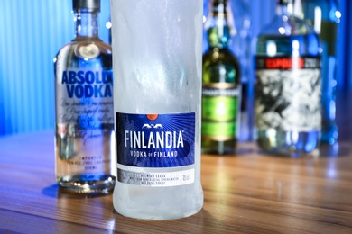 Photo of MYKOLAIV, UKRAINE - SEPTEMBER 24, 2019: Bottles of global vodka brands on wooden counter in bar