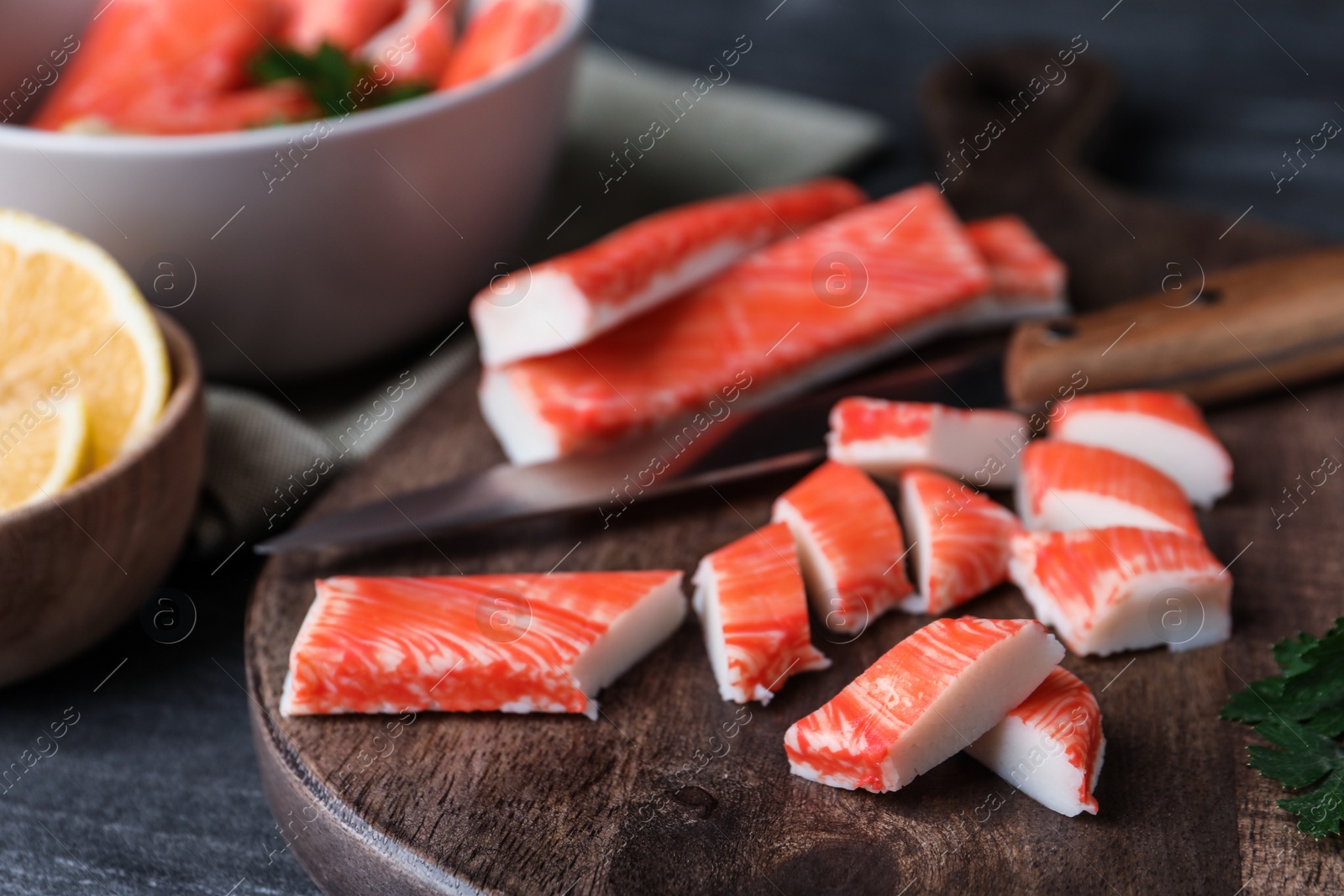 Photo of Fresh crab sticks, knife and lemon on grey table, closeup