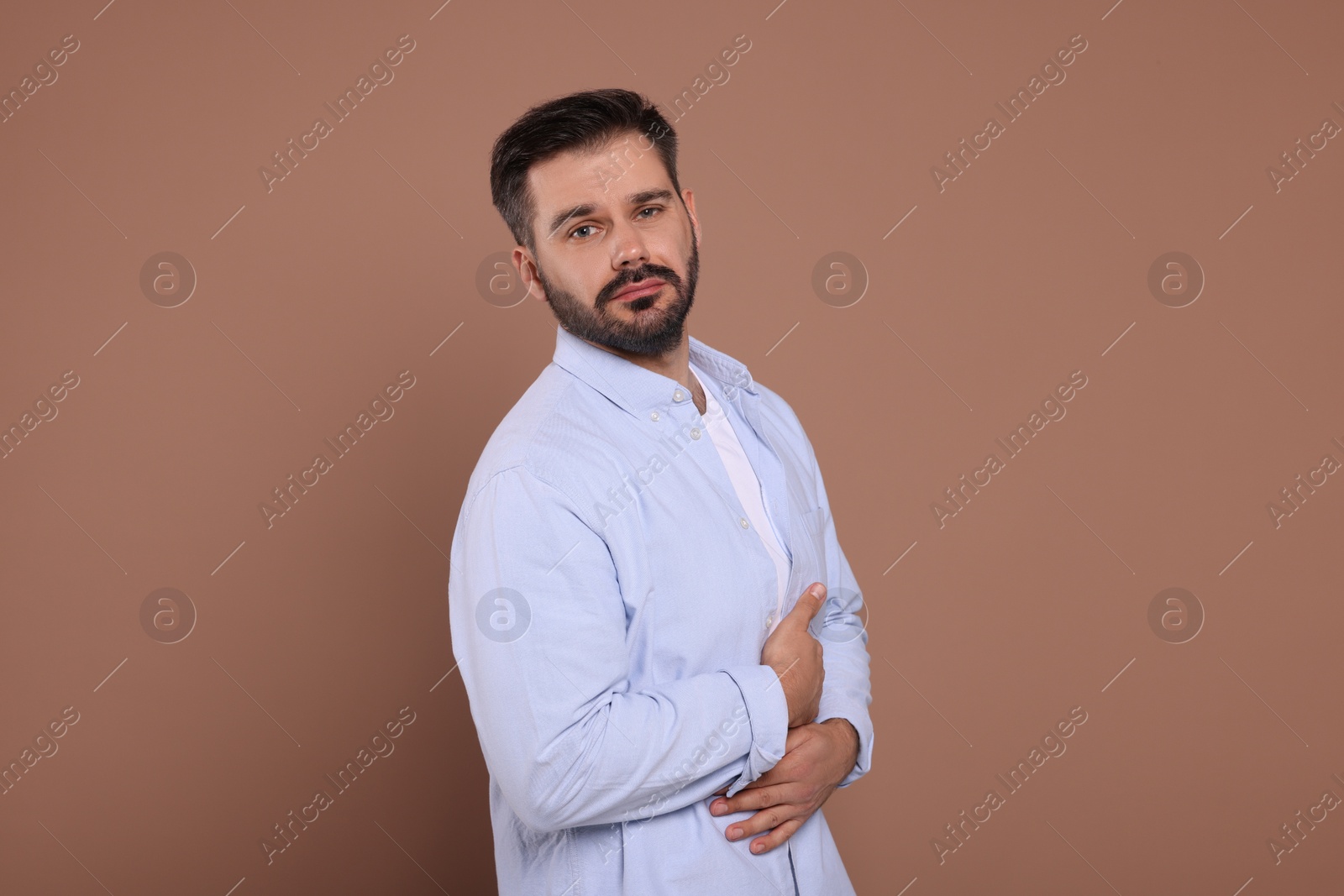 Photo of Man suffering from stomach pain on light brown background