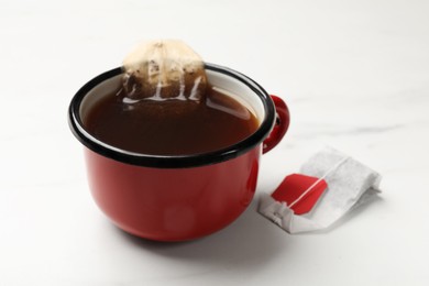 Photo of Tea bag in cup on white table, closeup