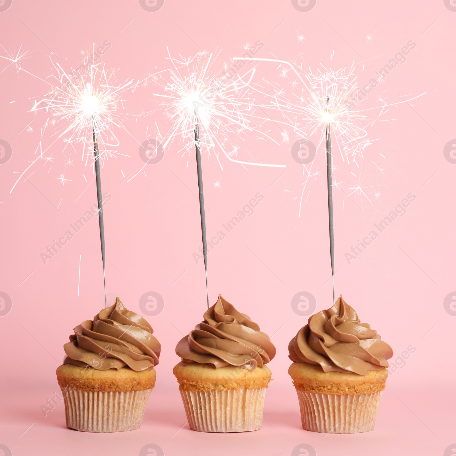 Image of Birthday cupcakes with sparklers on pink background