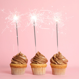 Birthday cupcakes with sparklers on pink background