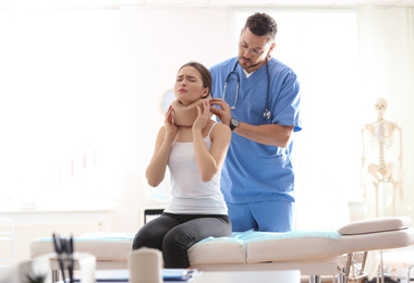 Photo of Male orthopedist applying cervical collar onto patient's neck in clinic