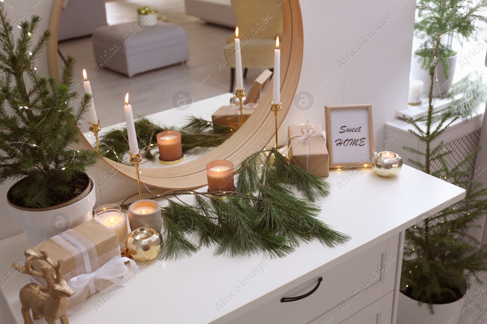 Photo of Mirror over chest of drawers with Christmas decor in room. Interior design