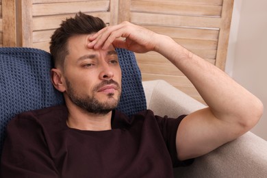 Photo of Upset man sulking on sofa at home. Loneliness concept