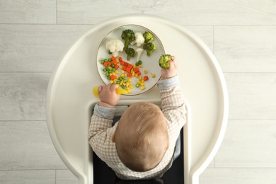 Photo of Cute little baby eating healthy food, top view