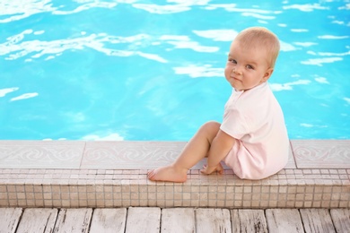 Photo of Little baby sitting near outdoor swimming pool. Dangerous situation