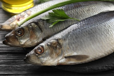 Delicious salted herrings and ingredients on black wooden table, closeup