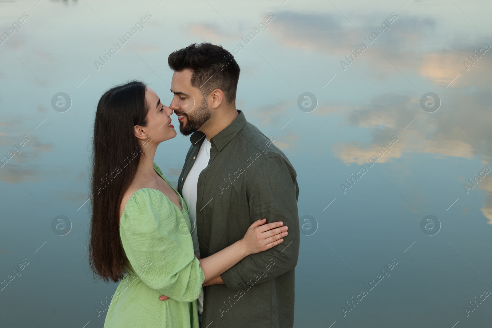 Photo of Romantic date. Beautiful couple spending time together near lake, space for text